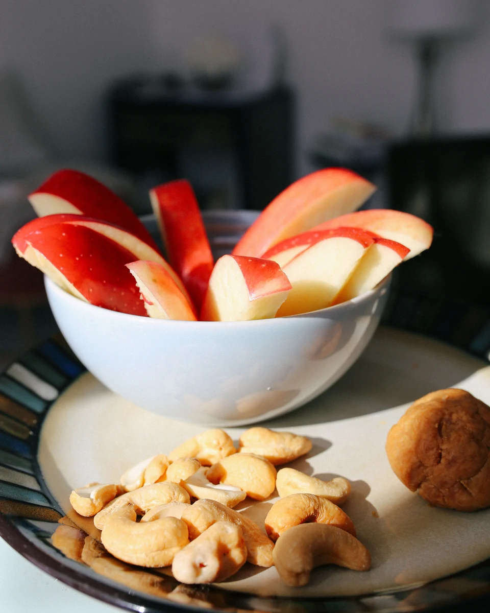 Cuenco con rodajas de manzana y un plato con anacardos