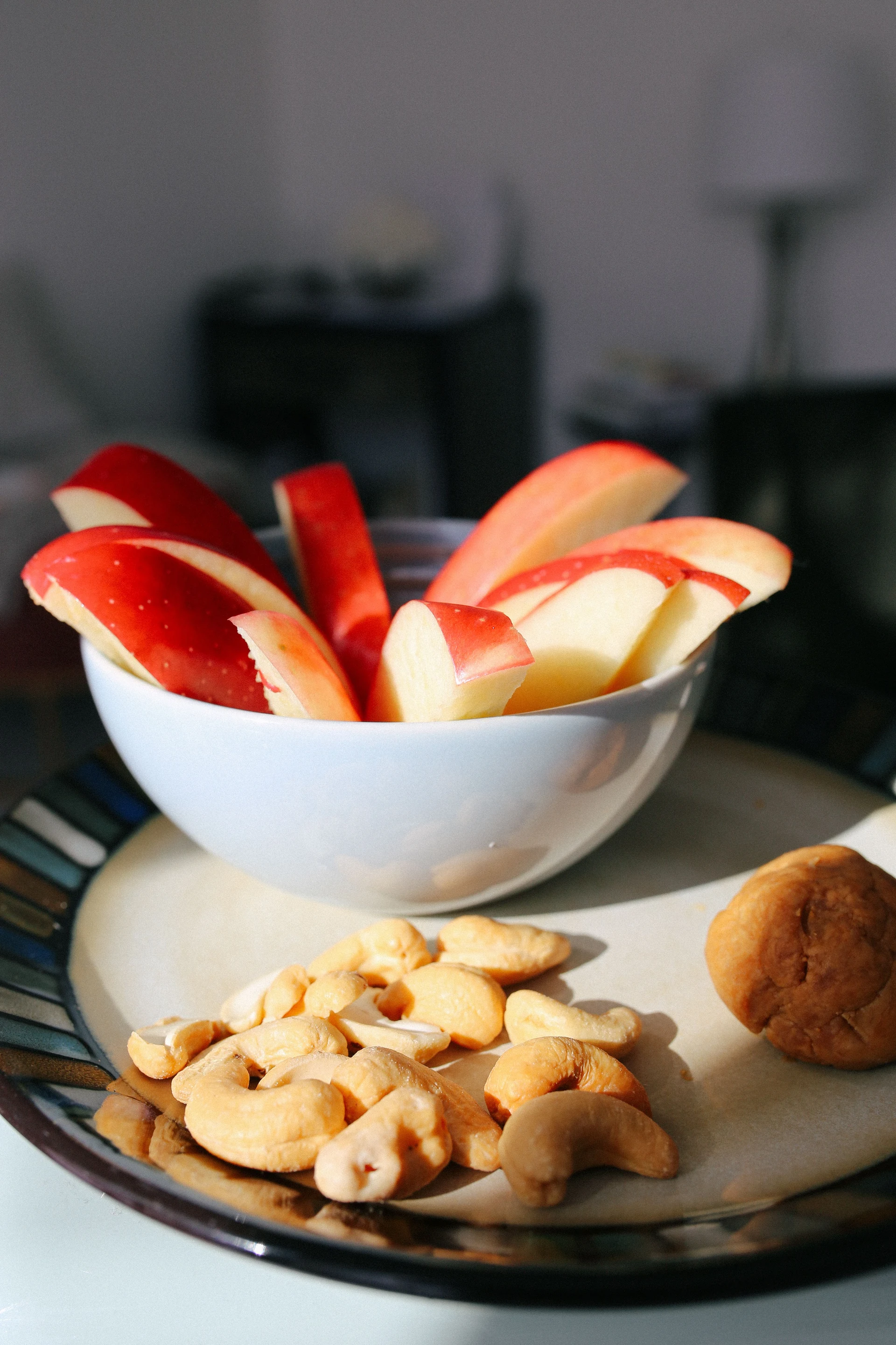 Cuenco con rodajas de manzana y un plato con anacardos