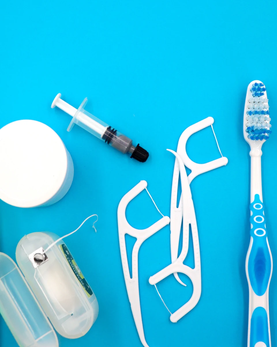 Cepillos, hilo dental y otros productos de higiene bucodental sobre fondo azul