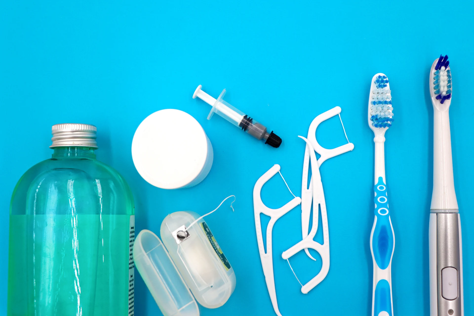 Cepillos, hilo dental y otros productos de higiene bucodental sobre fondo azul
