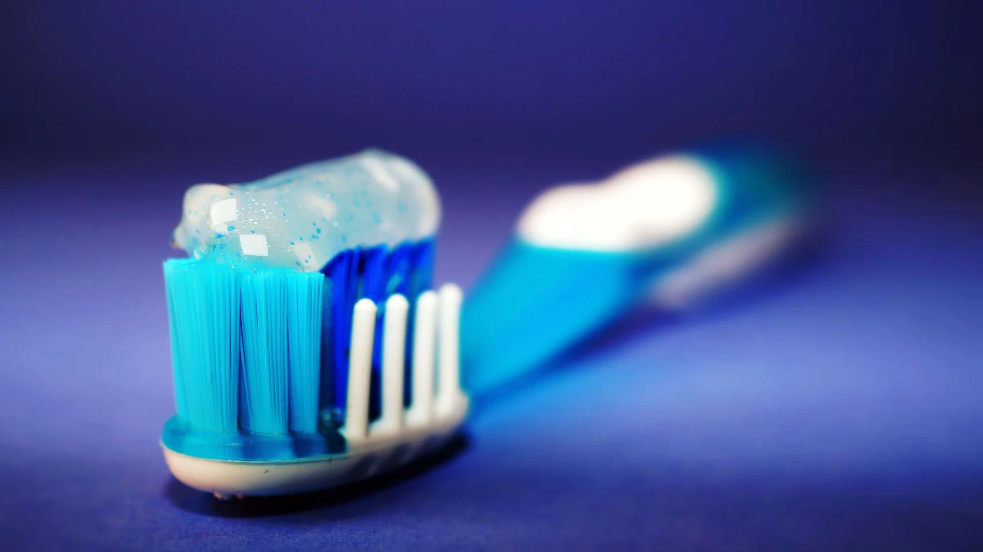 Primer plano de un cepillo de dientes con pasta dental azul