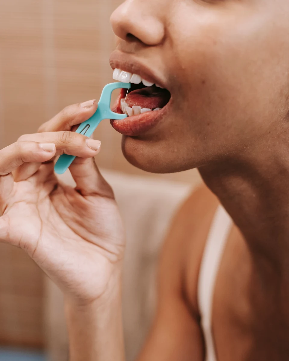 Persona utilizando un portahilo dental para limpiar entre los dientes