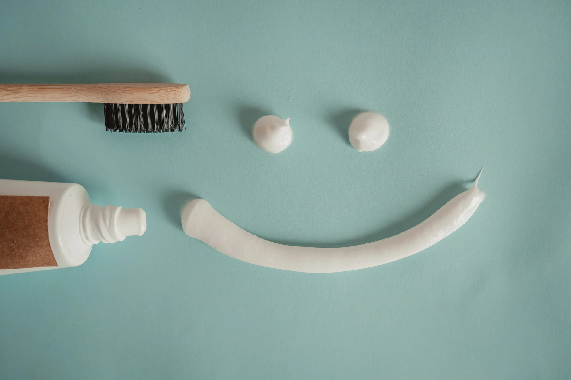 Cepillo y pasta de dientes formando una sonrisa sobre fondo verde