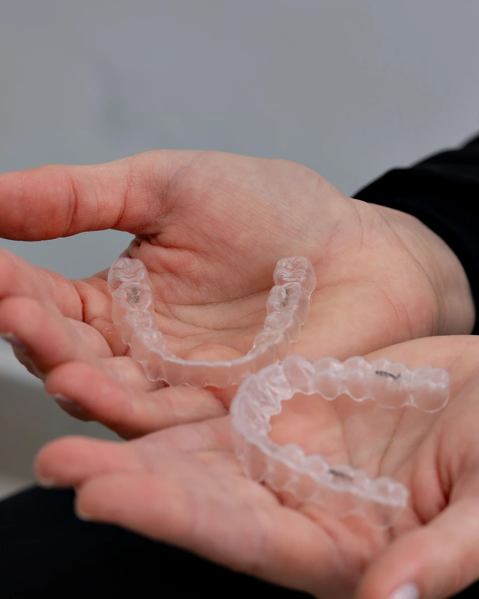 Dos alineadores dentales transparentes sostenidos en las manos